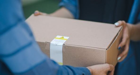 Ett brunt paket lämnas från en person till en annan.
