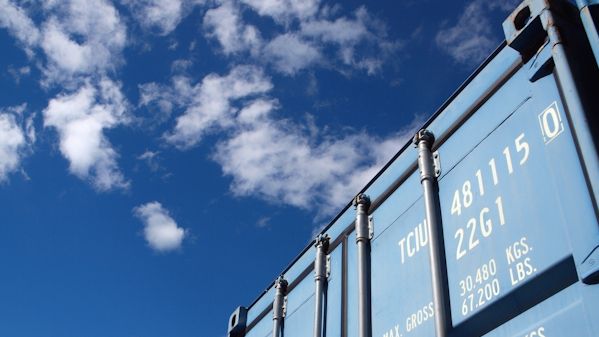 Ljusblå container mot en blå himmel med vita moln.