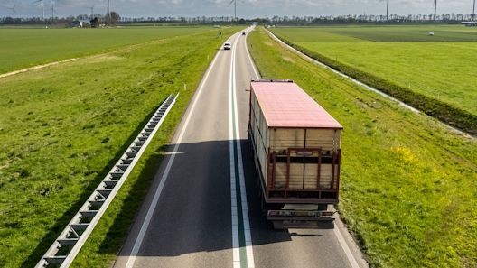 En lastbilstransport på en väg genom öppna landskap